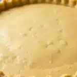 A close up of a 3 ingredient pie crust in a pie plate showcasing the flaky texture and crimped edges 2